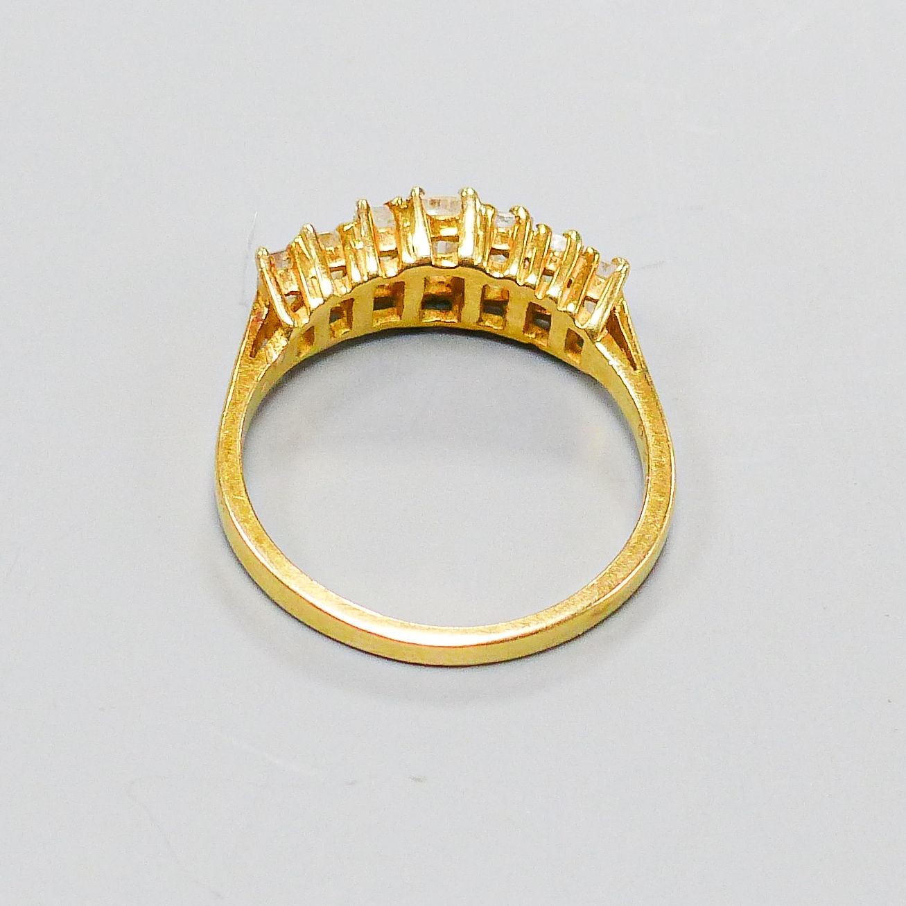 A modern 18ct gold and graduated seven stone baguette cut diamond set half hoop ring, size O, gross weight 4.1 grams.